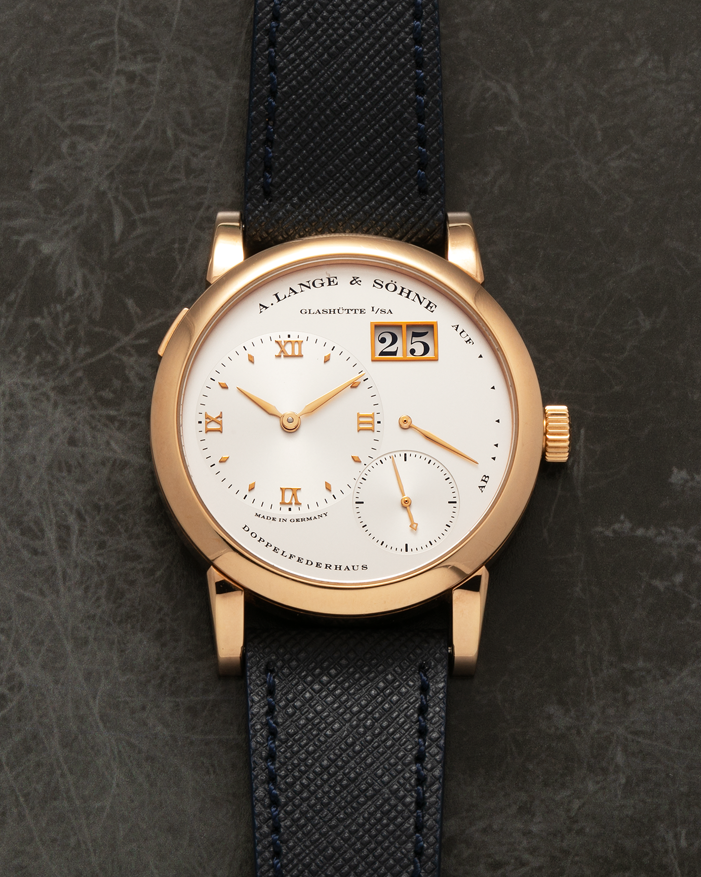 Brand: A. Lange & Sohne Year: 2000s Model: Lange 1 Reference: 101.032 Material: 18-carat Rose Gold, German Silver Movement: A. Lange & Söhne Cal. L901.0, Manual-Winding Case Diameter: 38.5mm Lug Width: 20mm Strap: Molequin Navy Blue Textured Calf Leather Strap with Signed 18-carat Rose Gold Tang Buckle, with additional A. Lange & Söhne Black Alligator Leather Strap (Used)