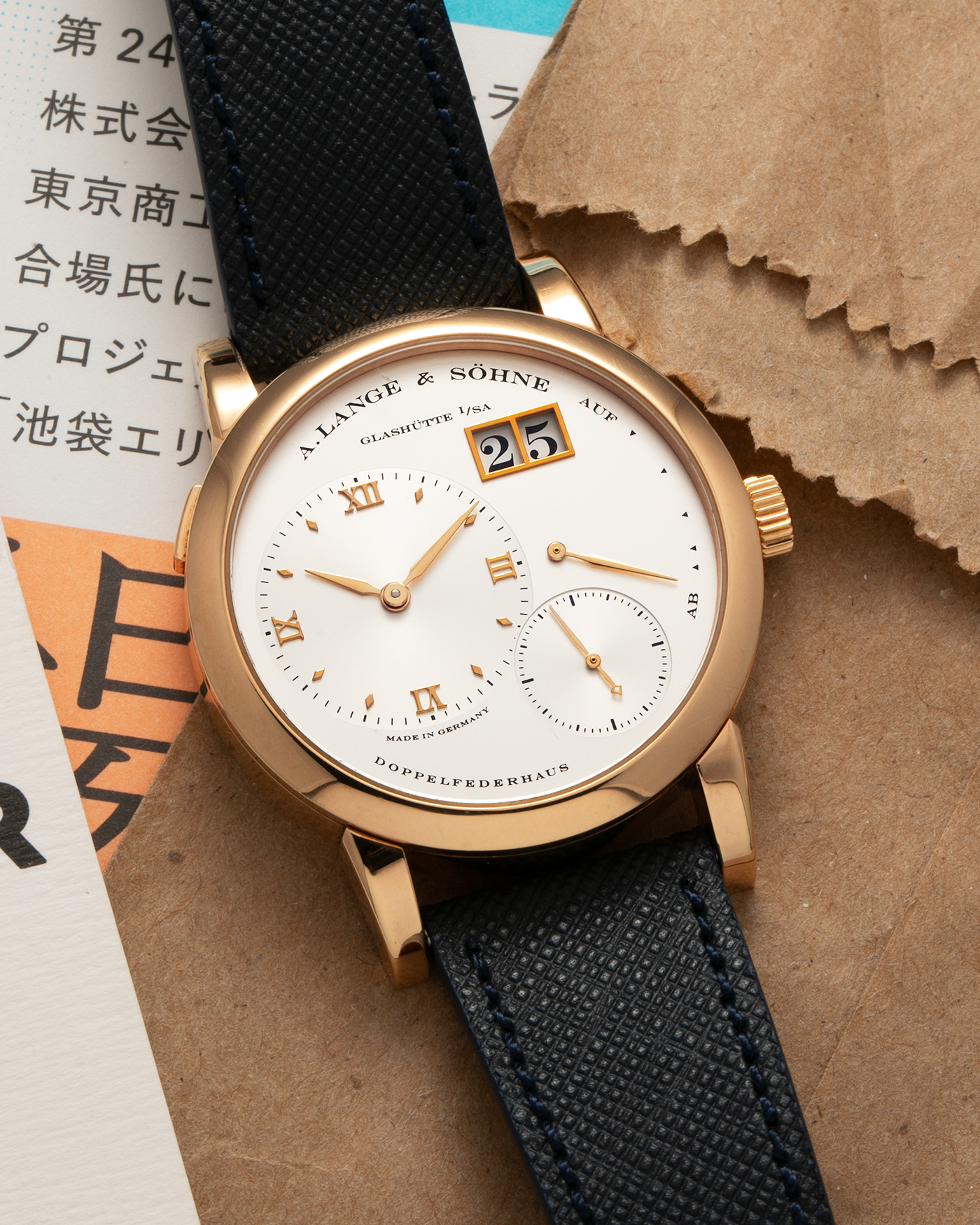 Brand: A. Lange & Sohne Year: 2000s Model: Lange 1 Reference: 101.032 Material: 18-carat Rose Gold, German Silver Movement: A. Lange & Söhne Cal. L901.0, Manual-Winding Case Diameter: 38.5mm Lug Width: 20mm Strap: Molequin Navy Blue Textured Calf Leather Strap with Signed 18-carat Rose Gold Tang Buckle, with additional A. Lange & Söhne Black Alligator Leather Strap (Used)