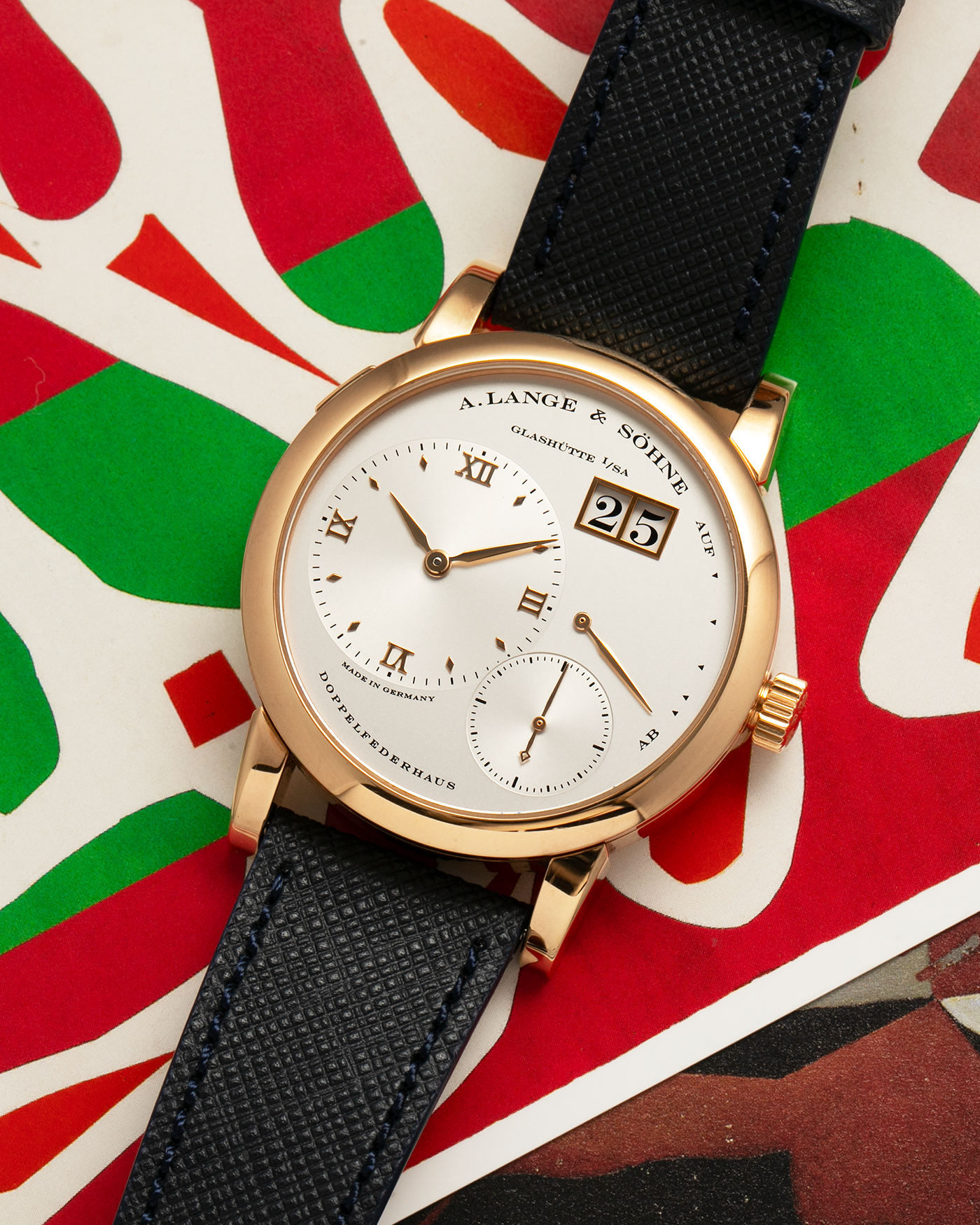 Brand: A. Lange & Sohne Year: 2000s Model: Lange 1 Reference: 101.032 Material: 18-carat Rose Gold, German Silver Movement: A. Lange & Söhne Cal. L901.0, Manual-Winding Case Diameter: 38.5mm Lug Width: 20mm Strap: Molequin Navy Blue Textured Calf Leather Strap with Signed 18-carat Rose Gold Tang Buckle, with additional A. Lange & Söhne Black Alligator Leather Strap (Used)