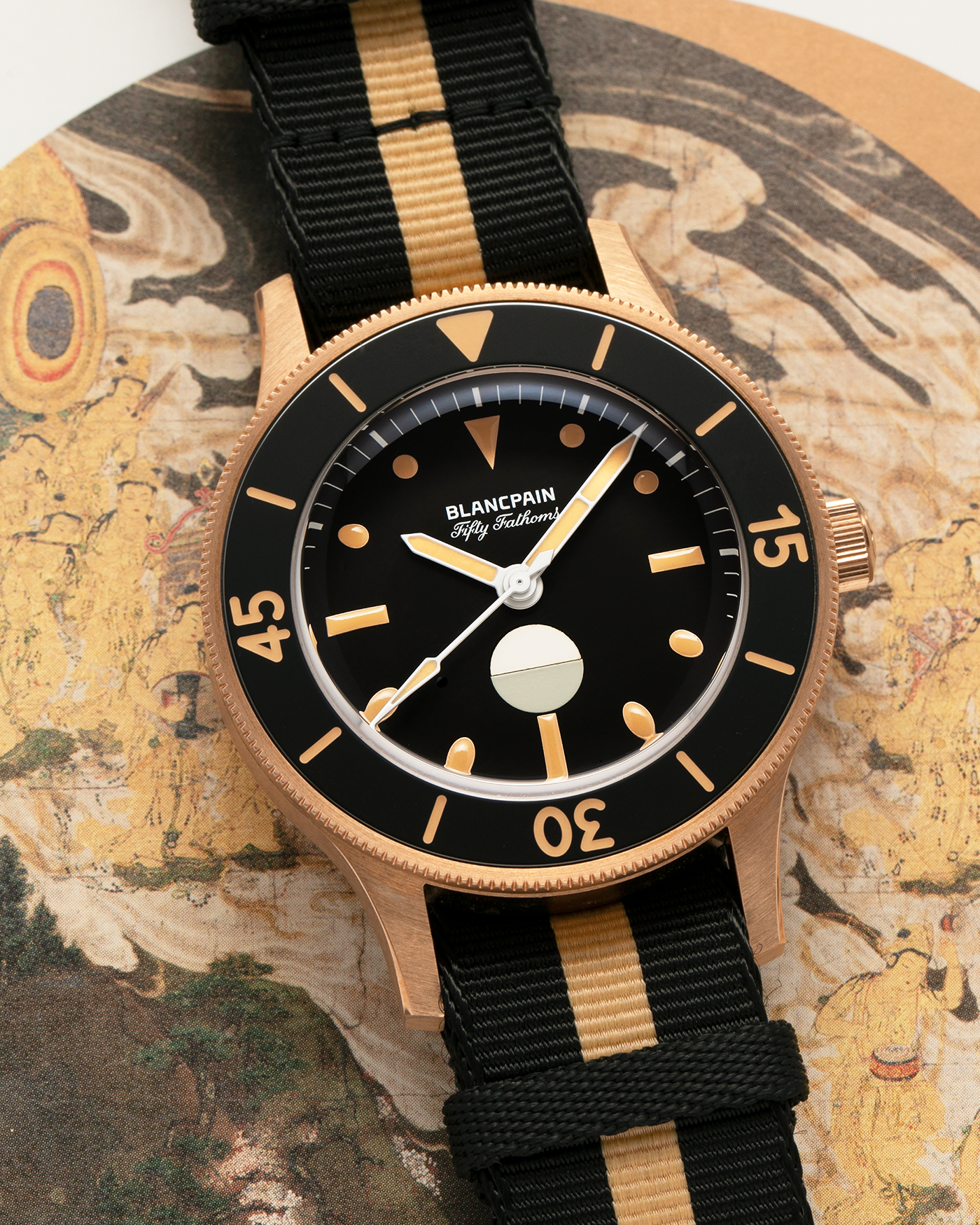 Brand: Blancpain
Year: 2024
Model: Fifty Fathoms 70th Anniversary Act 3, Limited Edition of 555 Pieces
Reference Number: 5901-5630 NANA
Material: 9-carat Bronze Gold, Black Ceramic Bezel Insert
Movement: Blancpain Cal. 1154.P2 (Derived from Blancpain Cal. 1150), Self-Winding
Case Dimensions: 41.3mm x 13.3mm (Lug-to-Lug 41.3mm)
Lug Width: 20mm
Strap: Blancpain Two-Tone NATO Strap with Signed 9-carat Bronze Gold Tang Buckle