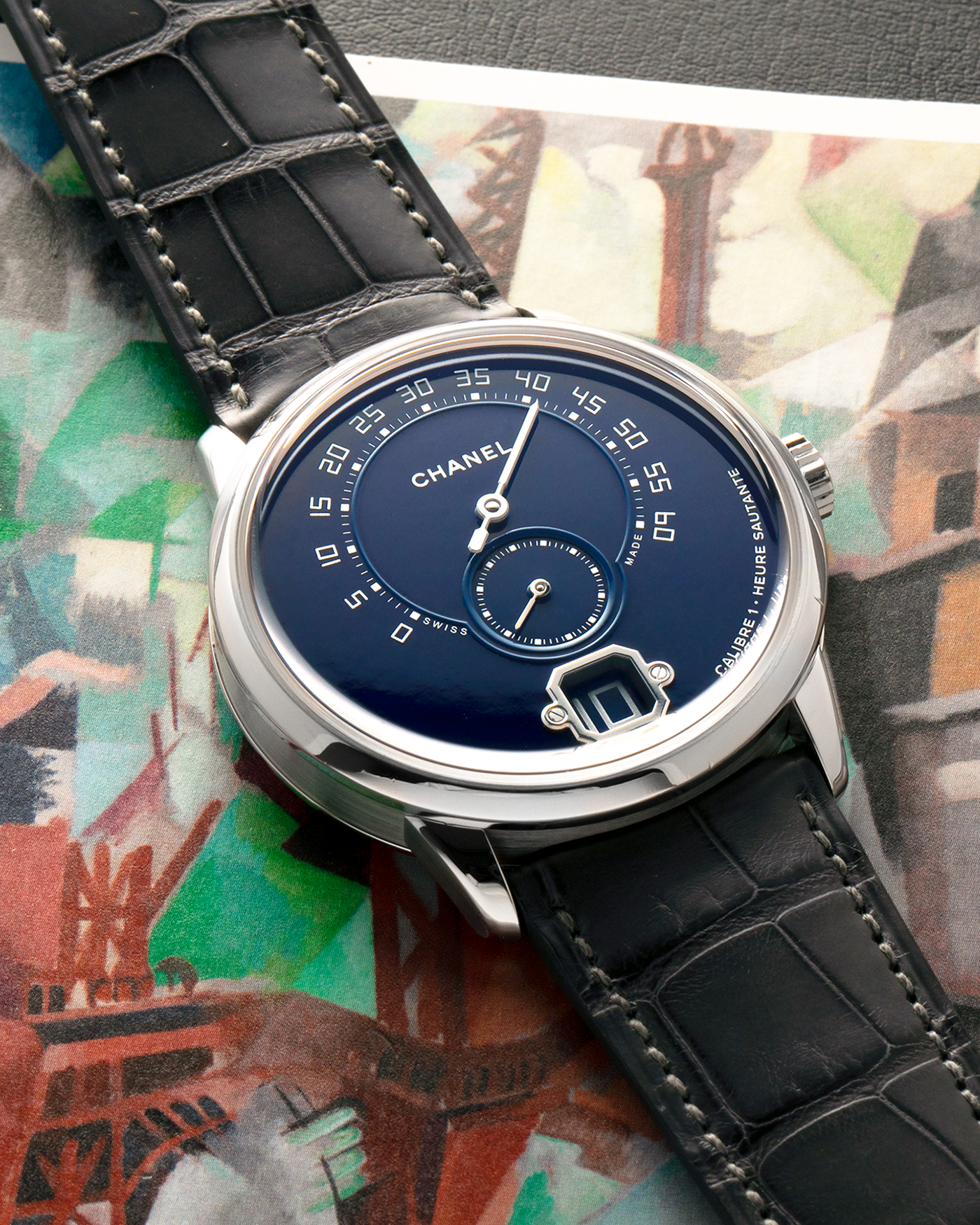 Brand: Chanel
Year: 2018
Model: Monsieur De Chanel Jump Hour, Limited to 20 Pieces
Reference: H5467
Material: Platinum 950 Case and Deployant Clasp, Blue Enamel Dial
Movement: Chanel Calibre 1 (Developed with Romain Gauthier), Manual-Winding 
Case Dimensions: 40mm x 10.4mm
Lug Width: 22mm
Straps: Chanel Grey Alligator Leather Strap with Signed Platinum 950 Deployant Clasp, with extra Chanel Black Alligator Leather Strap (Used)