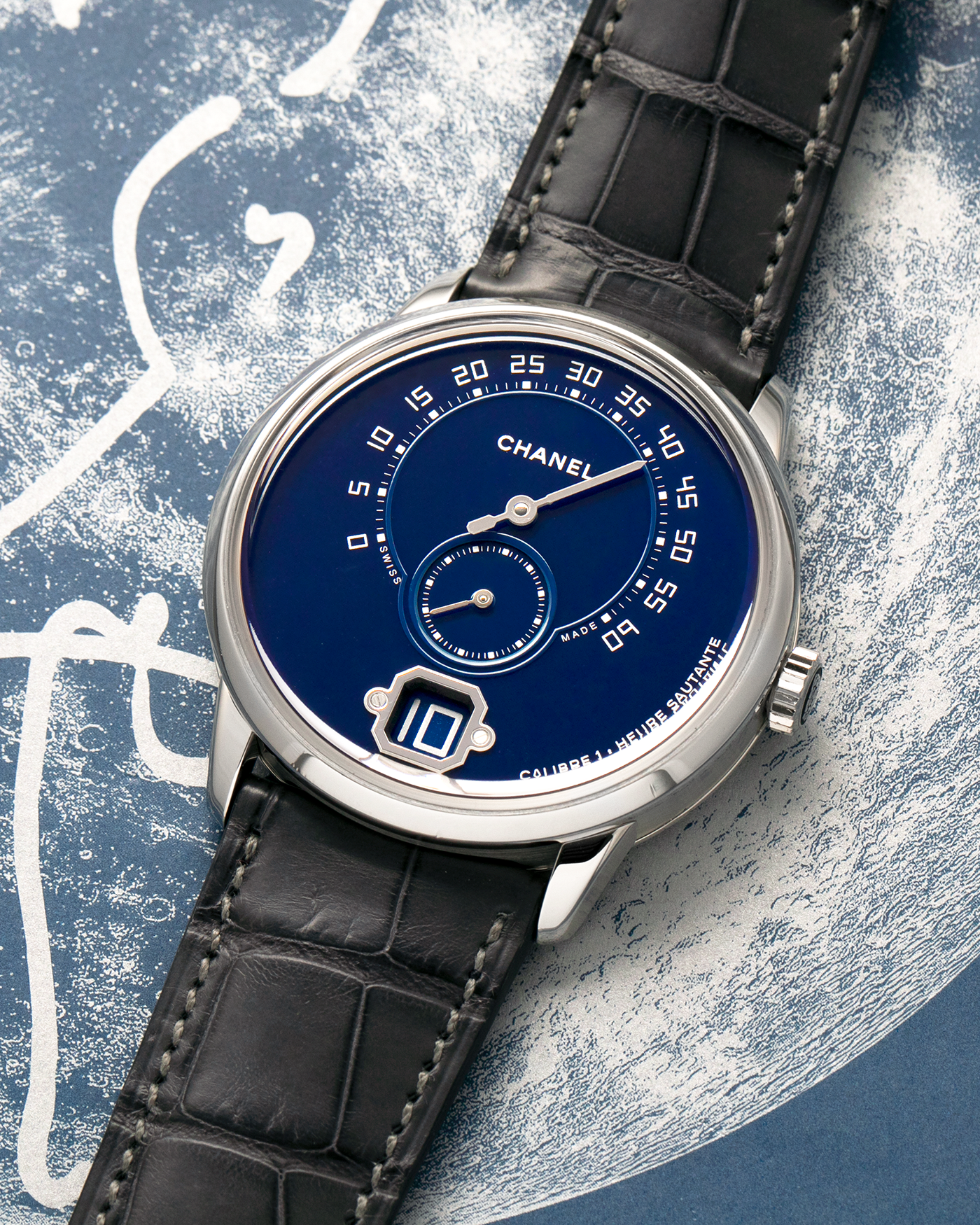 Brand: Chanel
Year: 2018
Model: Monsieur De Chanel Jump Hour, Limited to 20 Pieces
Reference: H5467
Material: Platinum 950 Case and Deployant Clasp, Blue Enamel Dial
Movement: Chanel Calibre 1 (Developed with Romain Gauthier), Manual-Winding 
Case Dimensions: 40mm x 10.4mm
Lug Width: 22mm
Straps: Chanel Grey Alligator Leather Strap with Signed Platinum 950 Deployant Clasp, with extra Chanel Black Alligator Leather Strap (Used)
