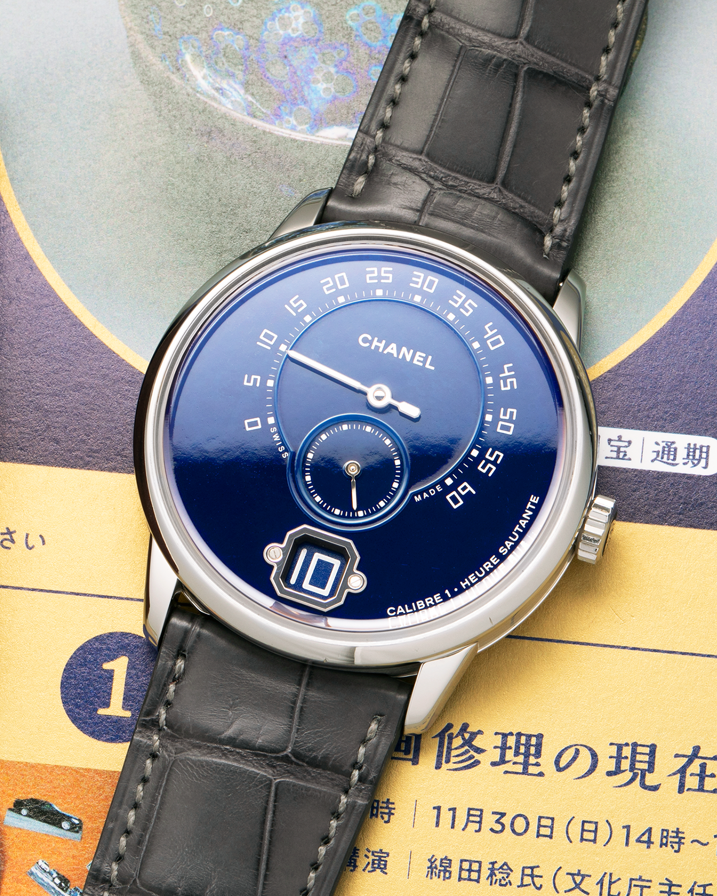 Brand: Chanel
Year: 2018
Model: Monsieur De Chanel Jump Hour, Limited to 20 Pieces
Reference: H5467
Material: Platinum 950 Case and Deployant Clasp, Blue Enamel Dial
Movement: Chanel Calibre 1 (Developed with Romain Gauthier), Manual-Winding 
Case Dimensions: 40mm x 10.4mm
Lug Width: 22mm
Straps: Chanel Grey Alligator Leather Strap with Signed Platinum 950 Deployant Clasp, with extra Chanel Black Alligator Leather Strap (Used)