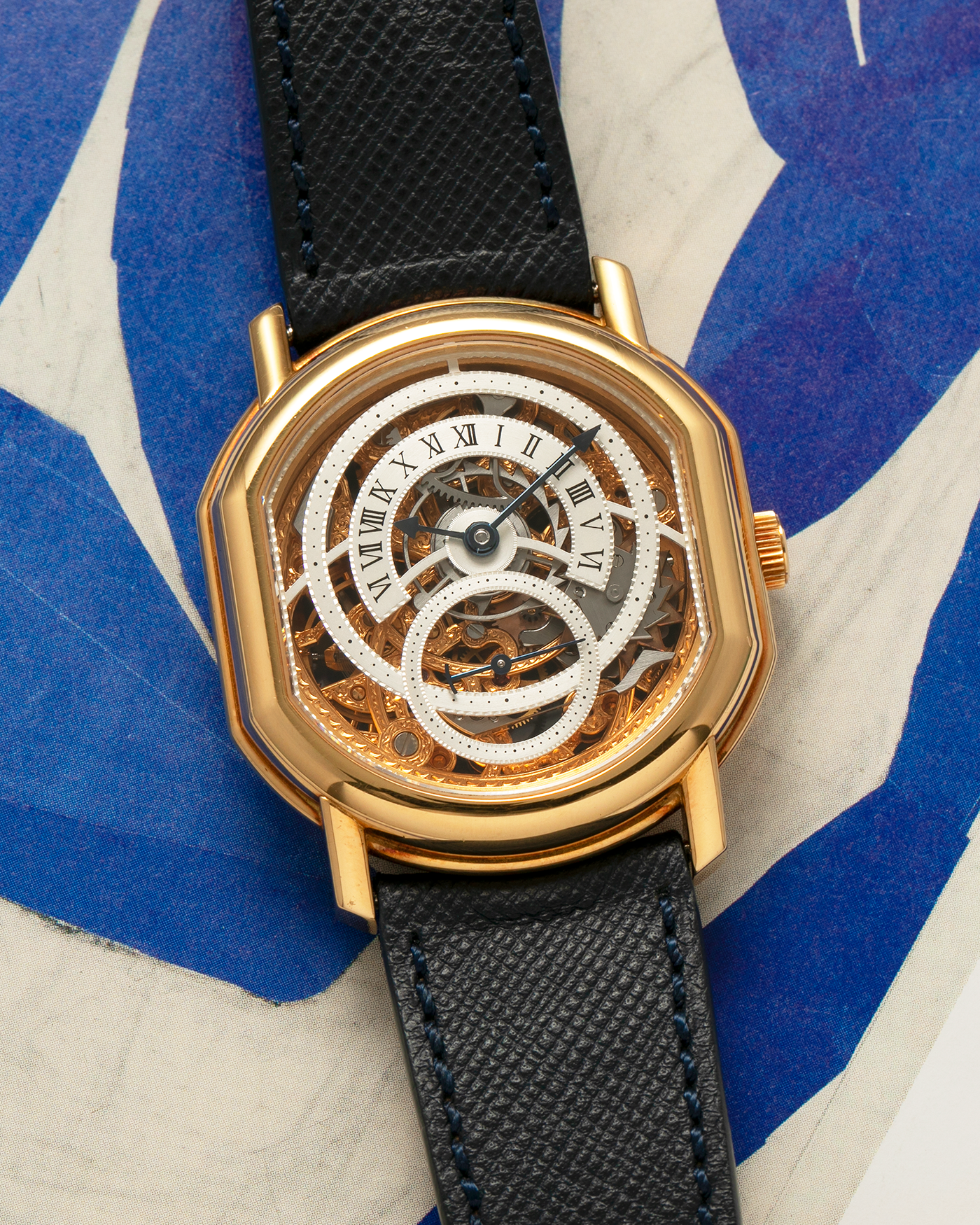 Brand: Daniel Roth
Year: 1990’s
Model: 2127 Retrograde Skeleton
Material: 18-carat Yellow Gold
Movement: Lemania Cal. 27LN with Retrograde Function, Manual-Winding
Case Diameter: 35mm x 38mm (41mm Lug-to-Lug)
Lug Width: 20mm
Strap: Molequin Navy Blue Grained Calf Strap with Signed 18-carat Yellow Gold Tang Buckle