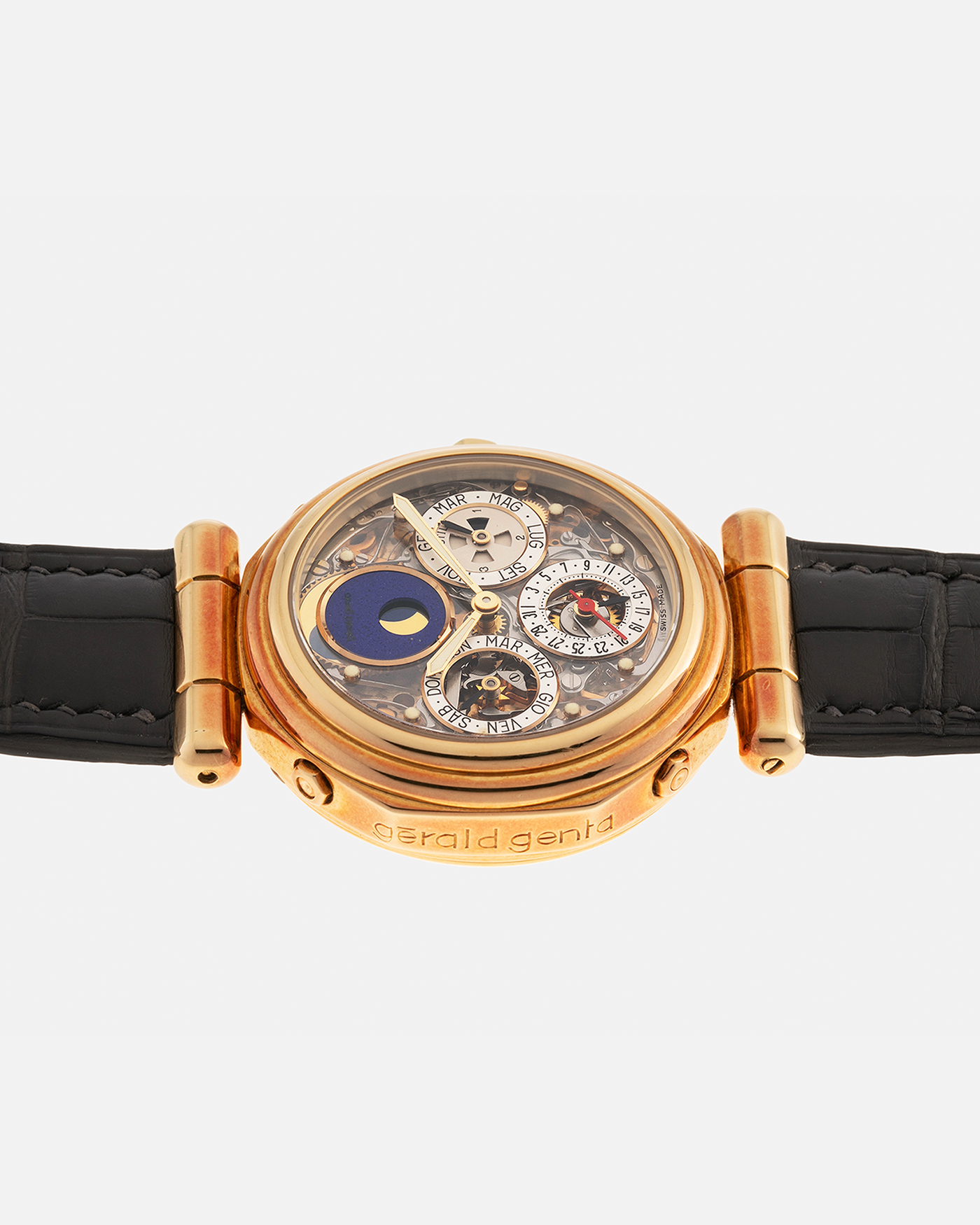 Brand: Gerald Genta
Year: 1990s
Serial Number: 47063
Reference Number: G.4009.4
Movement Number: 17
Material: 18-carat Yellow Gold Case, Lapis Lazuli Moon Phase
Movement: In-house Gilt Brass Caliber with Perpetual Calendar and Tourbillon, Self-Winding
Case Dimensions: 35mm x 11mm (Lug-to-Lug 43.8mm)
Lug Width: 19mm
Strap: Unnamed Custom Grey Alligator Leather Strap with Blue Underlining, additional Unnamed Brown Suede Calf Leather Strap with Signed 18-carat Yellow Gold Butterfly Clasp and Original Gold Stra