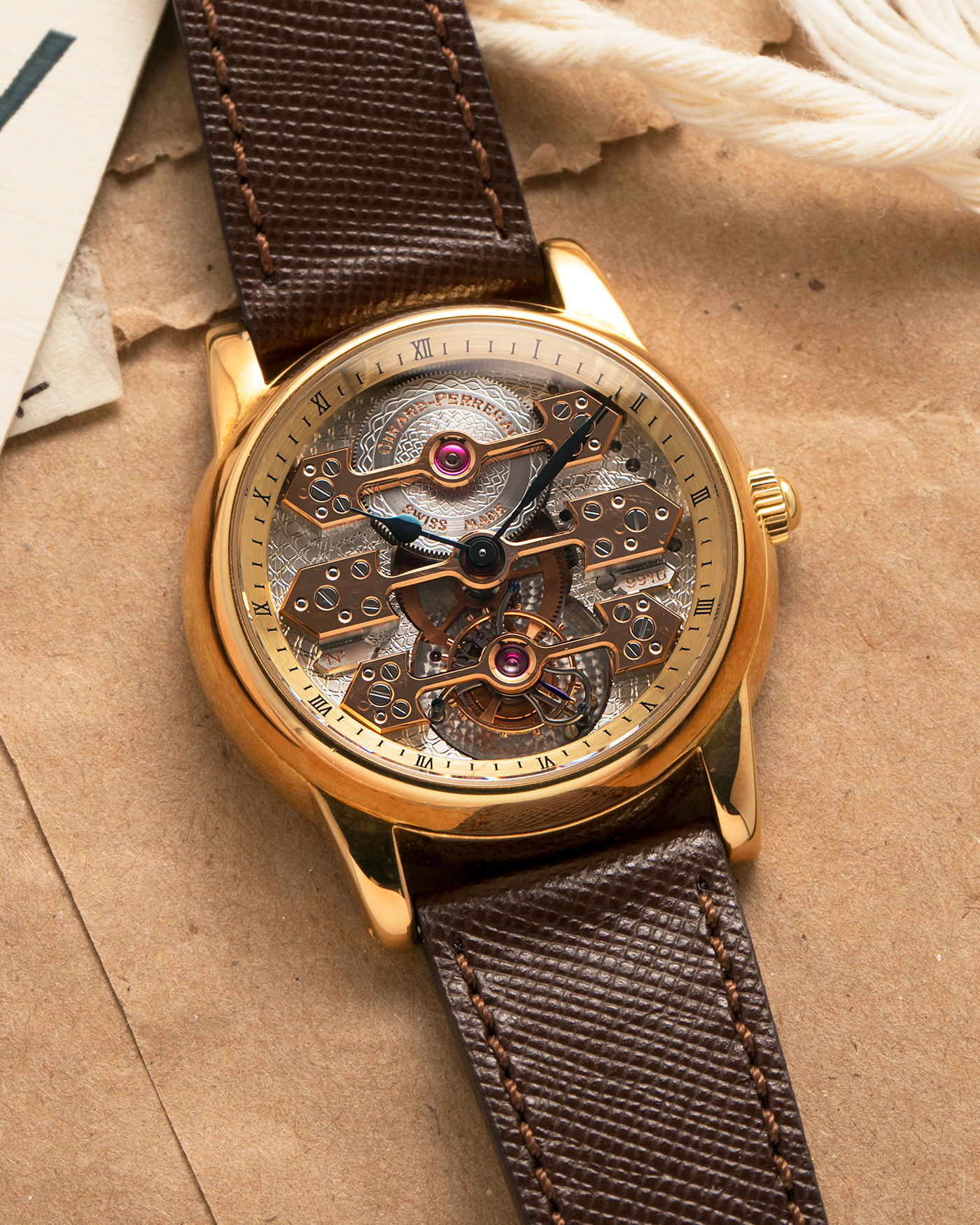 Brand: Girard Perregaux  Year: Mid-1990s Model: Three Bridges Tourbillon, “Tourbillon Sous Trois Ponts d'Or” Reference: 99000 Material: 18-carat Yellow Gold  Movement: Girard Perregaux Cal. 9910 Tourbillon, Manual-Winding  Case Dimensions: 39mm x 10.5mm (Lug-to-Lug 44.5mm)  Lug Width: 20mm  Strap: Phillips Dark Brown Textured Calf Leather Strap with Signed 18-carat Yellow Gold Tang Buckle 