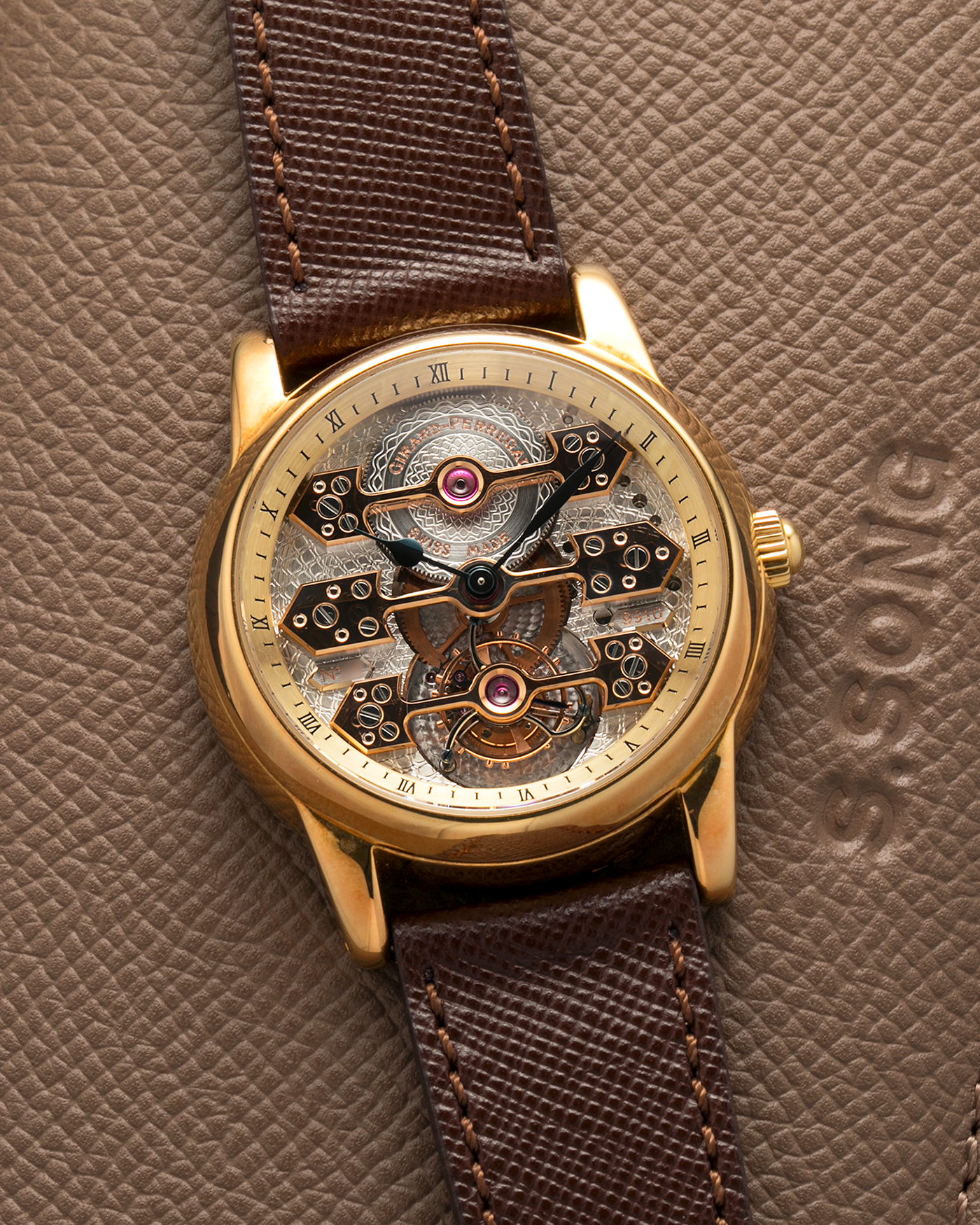 Brand: Girard Perregaux  Year: Mid-1990s Model: Three Bridges Tourbillon, “Tourbillon Sous Trois Ponts d'Or” Reference: 99000 Material: 18-carat Yellow Gold  Movement: Girard Perregaux Cal. 9910 Tourbillon, Manual-Winding  Case Dimensions: 39mm x 10.5mm (Lug-to-Lug 44.5mm)  Lug Width: 20mm  Strap: Phillips Dark Brown Textured Calf Leather Strap with Signed 18-carat Yellow Gold Tang Buckle 