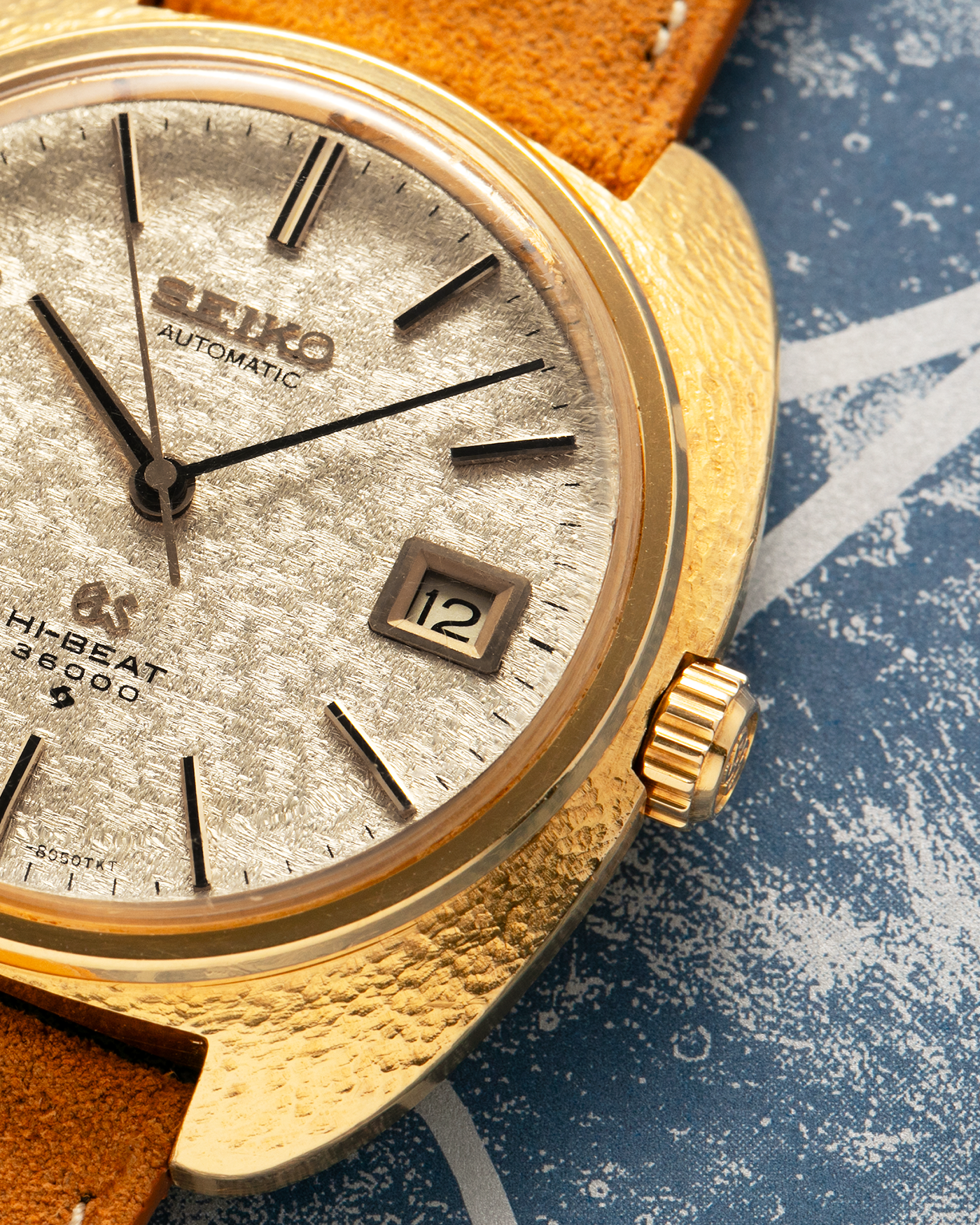 Brand: Grand Seiko
Year: Late 1960’s/1970’s
Model: 61GS
Reference Number: 6145-8030 ‘Kirazuri’
Material: 18-carat Yellow Gold
Movement: Self-Winding Hi Beat Cal. 6145
Case Dimensions: 37mm Diameter 11mm Thickness
Lug Width: 18mm
Strap: Nostime Tan Suede Strap with Generic Stainless Steel Buckle