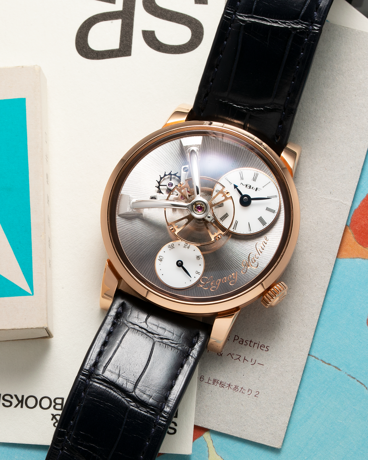 Brand: MB&F Year: 2022 Model: Legacy Machine 101 ‘Red Gold’ Reference: 51.RL.W Material: 18-carat Red Gold Movement: In-House 3-Dimensional MB&F Caliber in Collaboration with Kari Voutilainen, Manual-Winding Case Dimensions: 40mm x 16mm Lug Width: 21mm Strap: MB&F Dark Navy Alligator Strap and Signed Palladium Deployant Clasp
