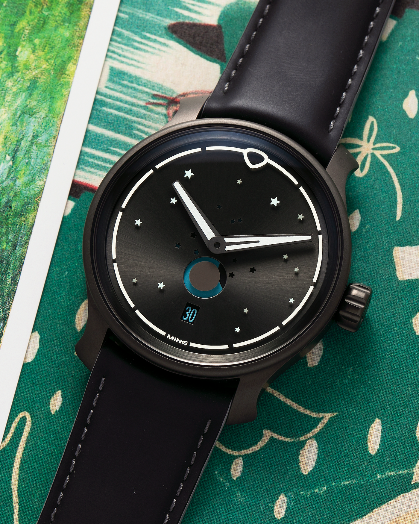 Brand: MING Year: 2023 Model: 37.05 Moonphase Series 2 Special Edition (Special Caves Project), Limited to 50 pieces Material: DLC-Coated Stainless Steel Movement: Heavily Modified Sellita Cal. SW288-1, Manual-Winding Case Diameter: 38mm Lug Width: 20mm Strap: Jean Rousseau Black Rubber with Blue Under Lining for MING with Signed DLC-Coated Keeperless Flying Blade Buckle