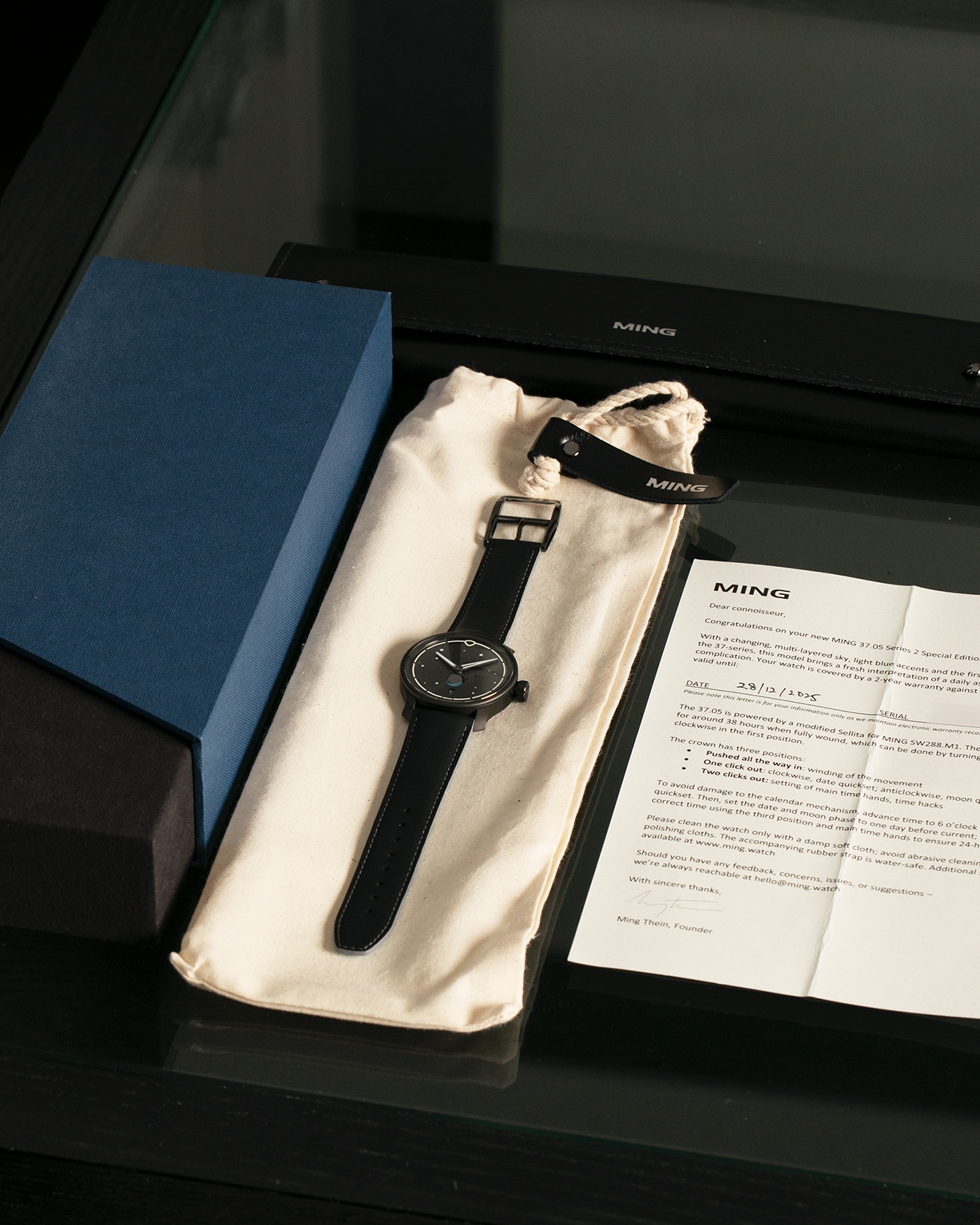 Brand: MING Year: 2023 Model: 37.05 Moonphase Series 2 Special Edition (Special Caves Project), Limited to 50 pieces Material: DLC-Coated Stainless Steel Movement: Heavily Modified Sellita Cal. SW288-1, Manual-Winding Case Diameter: 38mm Lug Width: 20mm Strap: Jean Rousseau Black Rubber with Blue Under Lining for MING with Signed DLC-Coated Keeperless Flying Blade Buckle