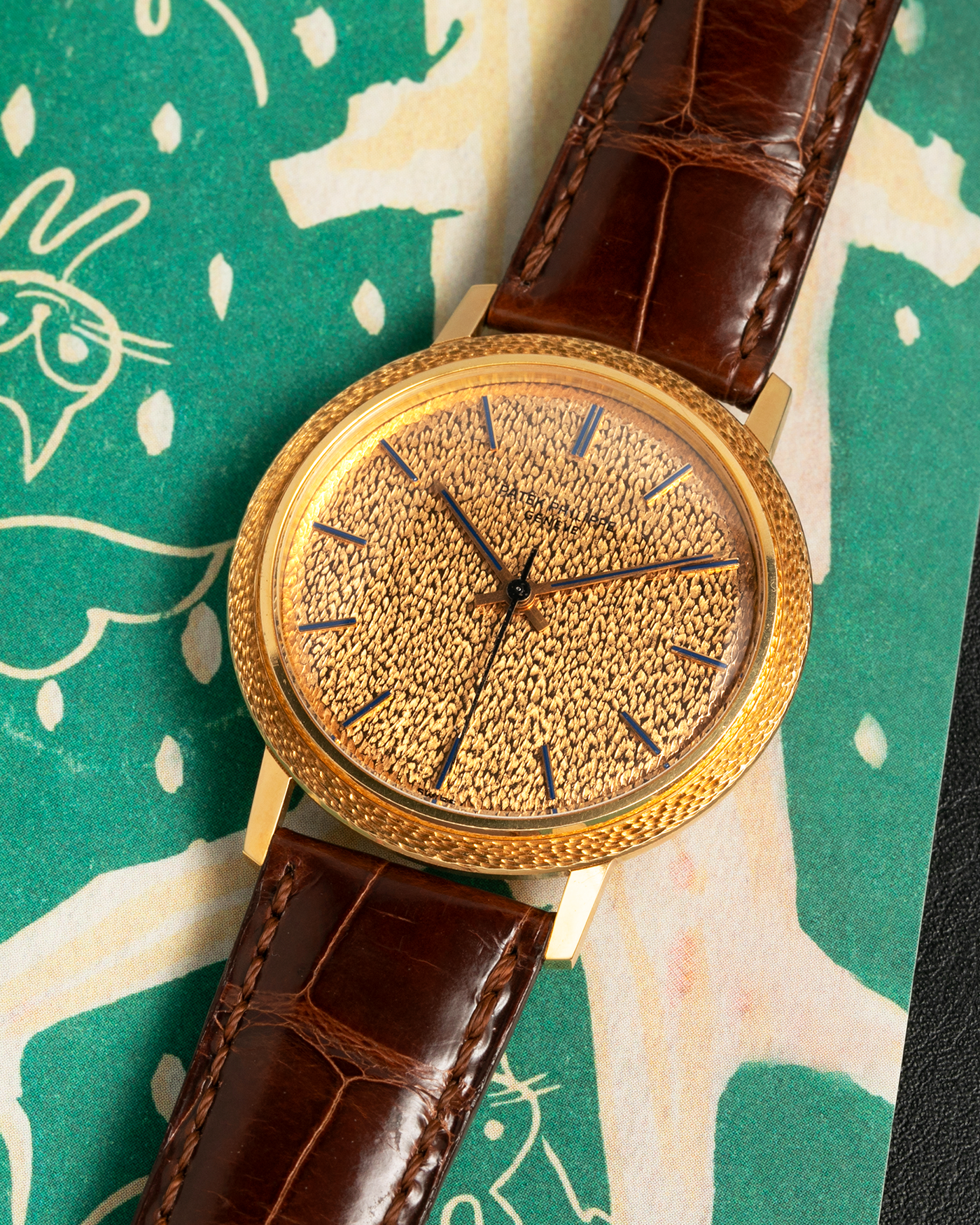 Brand: Patek Philippe
Year: 1970
Model: Calatrava ‘Back Wind’ Hammered
Reference Number: 3569J
Material: 18-carat Yellow Gold
Movement: Patek Philippe Back-Wind Cal. 350, Self-Winding
Case Dimensions: 36mm x 8.3mm (Lug-to-Lug 41mm)
Lug Width: 18mm
Strap: Patek Philippe Dark Brown Alligator Leather Strap with Signed 18-carat Yellow Gold Tang Buckle