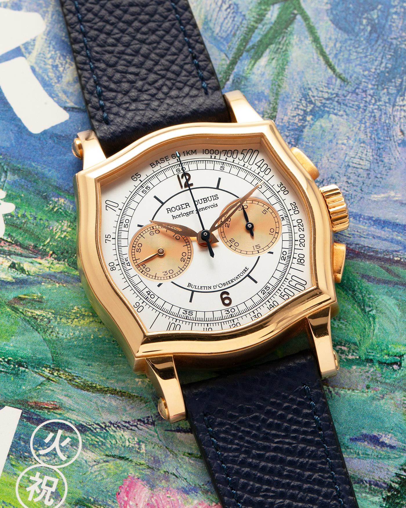 Brand: Roger Dubuis
Year: Late 1990’s/2000’s
Model: Sympathie 37 Perpetual Chronograph
Material: 18k Rose Gold
Movement: Cal RD56 / Lemania 2310
Case Diameter: 37mm
Strap: Nostime Blue Textured Calf Strap and Roger Dubuis 18k Rose Gold Tang Buckle