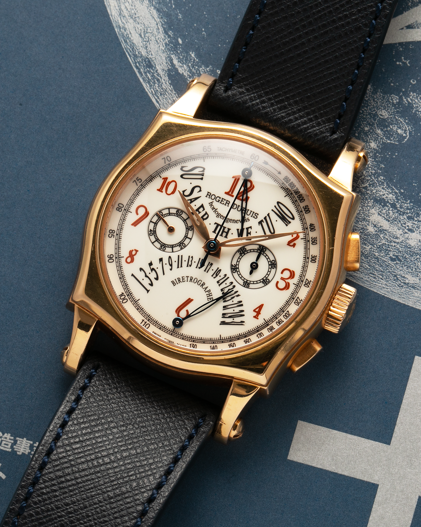Brand: Roger Dubuis Year: 2000’s Model: Sympathie 40 Biretrograde Chronograph Material: 18-carat Yellow Gold Movement: Roger Dubuis Cal. RD 5630 (Based on the Lemania Cal. 2310), Manual-Winding Case Diameter: 40mm Strap: Molequin Navy Blue Textured Calf Leather Strap with Signed 18-carat Yellow Gold Roger Dubuis Tang Buckle