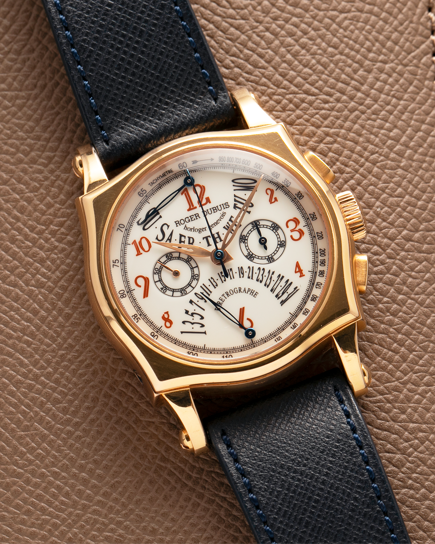 Brand: Roger Dubuis
Year: 2000s
Model: Sympathie 40 Biretrograde Chronograph
Material: 18-carat Yellow Gold
Movement: Roger Dubuis Cal. RD 5630 (Based on the Lemania Cal. 2310), Manual-Winding
Case Dimensions: 40mm x 12.25mm (Lug-to-Lug 47mm)
Lug Width: 22mm
Strap: Molequin Navy Blue Textured Calf Leather Strap with Signed 18-carat Yellow Gold Tang Buckle