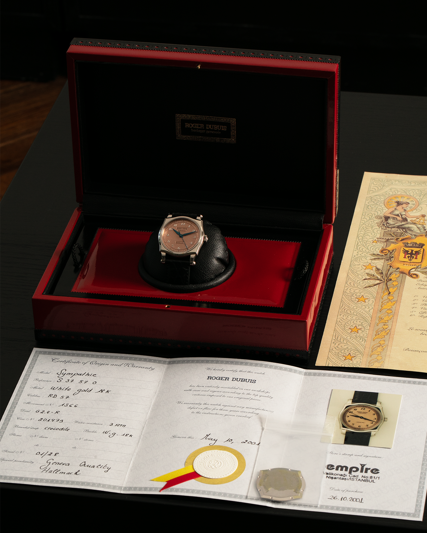 Brand: Roger Dubuis
Year: 2001
Model: Sympathie 37 ‘Salmon Guilloché’, Limited to 28 Pieces
Reference: S37.57.0
Material: 18-carat White Gold
Movement: Roger Dubuis Cal. RD 57, Self-Winding
Case Dimensions: 37mm x 8.5mm (Lug-to-Lug 46.5mm)
Lug Width: 20mm
Strap: Roger Dubuis Black Crocodile Leather Strap with Signed 18-carat White Gold Tang Buckle