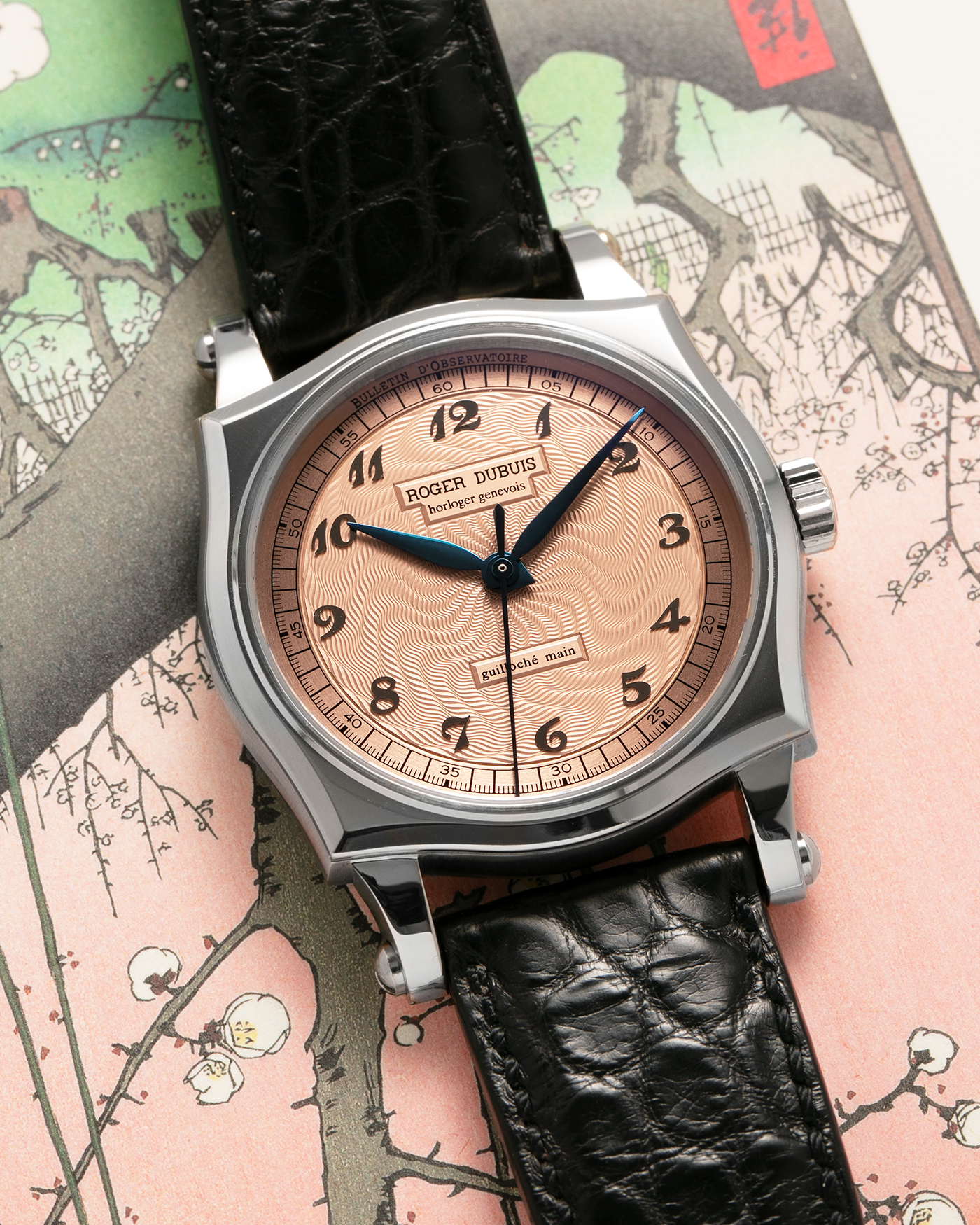 Brand: Roger Dubuis
Year: 2001
Model: Sympathie 37 ‘Salmon Guilloché’, Limited to 28 Pieces
Reference: S37.57.0
Material: 18-carat White Gold
Movement: Roger Dubuis Cal. RD 57, Self-Winding
Case Dimensions: 37mm x 8.5mm (Lug-to-Lug 46.5mm)
Lug Width: 20mm
Strap: Roger Dubuis Black Crocodile Leather Strap with Signed 18-carat White Gold Tang Buckle