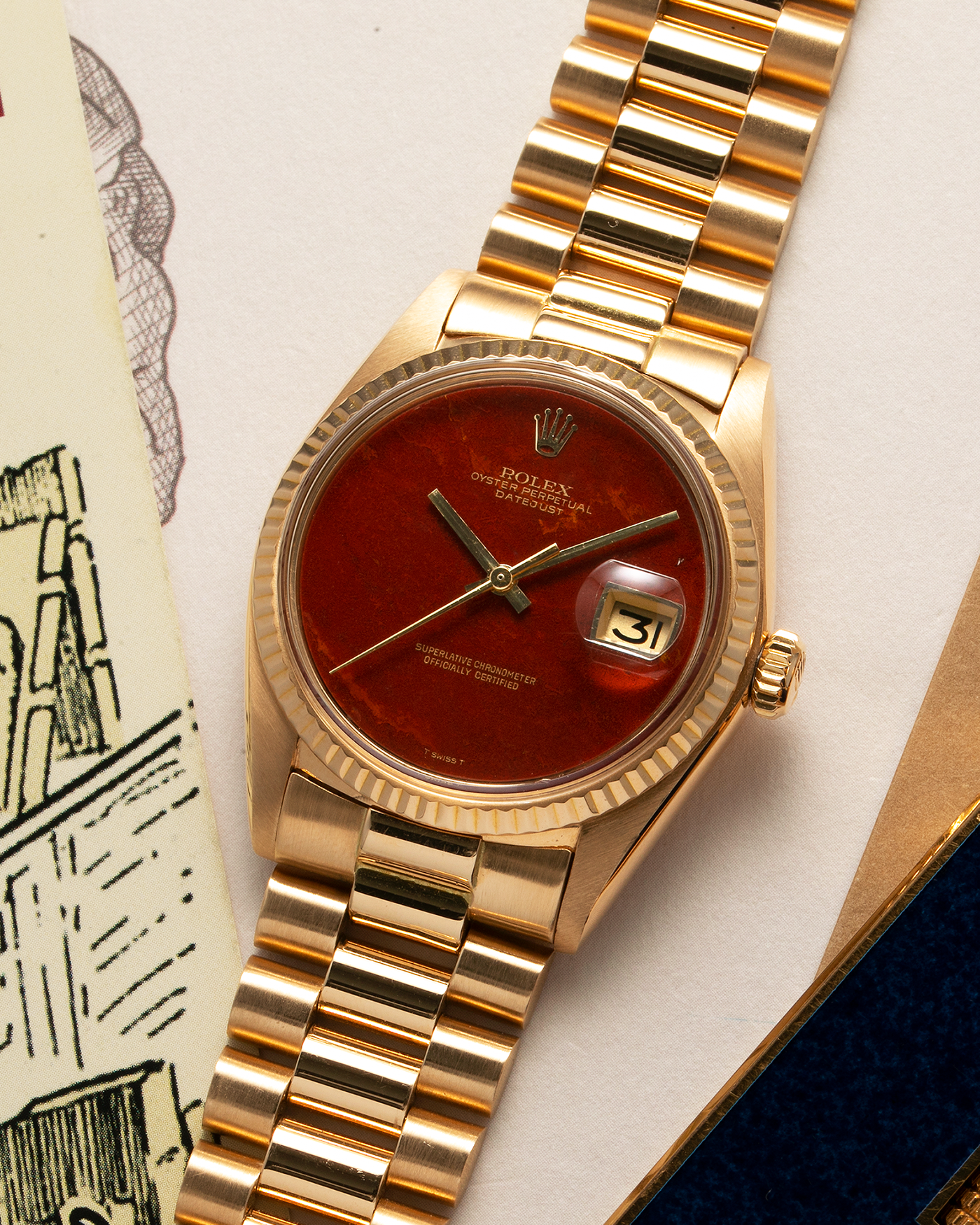 Brand: Rolex Year: 1975 Model: Datejust Reference Number: 1601/8 Serial Number: 392XXXX Material: 18-carat Yellow Gold, Red Jasper Stone Dial Movement: Rolex Cal. 1565, Self-Winding Case Diameter: 36mm Lug Width: 20mm Bracelet: Rolex 18-carat Yellow Gold 8385 Presidential Bracelet with 55B Curved End Links