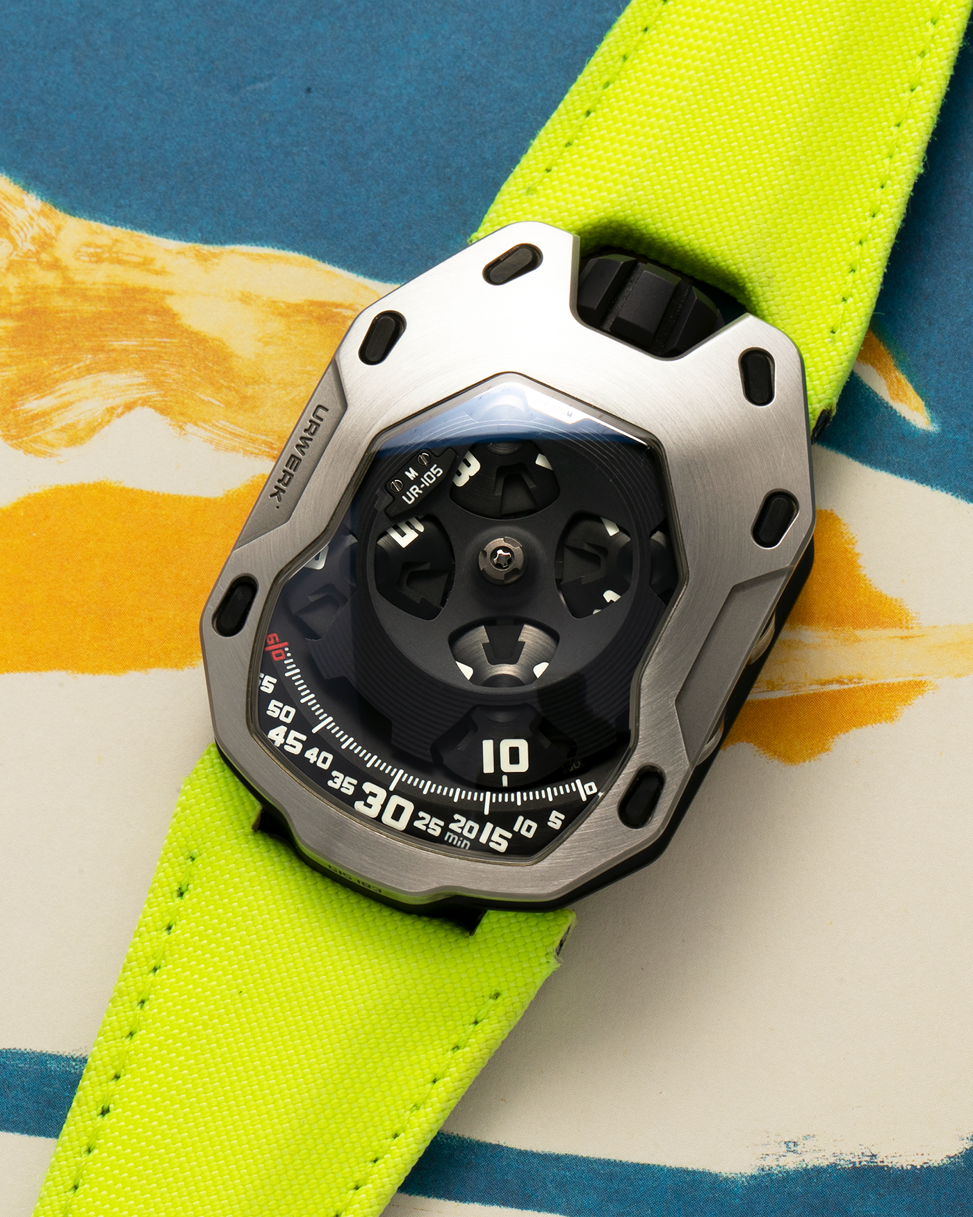 Brand: Urwerk Year: 2014 Model: UR105M “Iron Knight”, Limited to 77 pieces Material: Stainless Steel, Titanium Movement: Urwerk Cal. 5.01, Manual-Winding Case Dimensions: 39.50mm x 53mm x 16.65mm Strap: Urwerk Fluorescent Yellow Textile Strap with Signed Titanium Tang Buckle