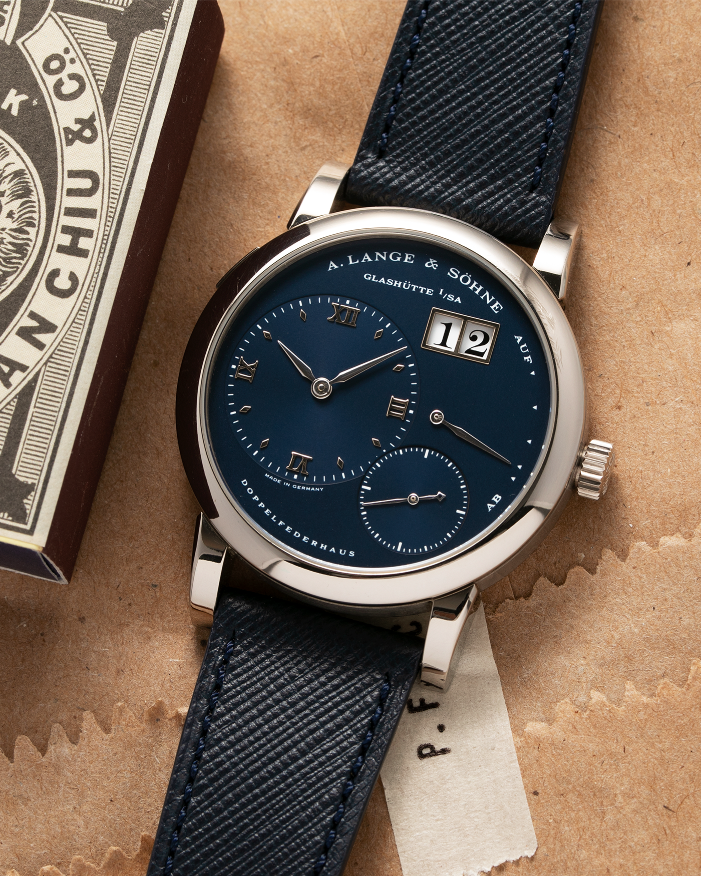Brand: A. Lange & Sohne Year: 2000’s Model: Lange 1  Reference Number: 101.027 Material: 18k White Gold Movement: Manual Winding L901.5 Case Diameter: 38.5mm Bracelet/Strap: Molequin Navy Blue Textured Calf with 18k White Gold A. Lange & Sohne Tang Buckle