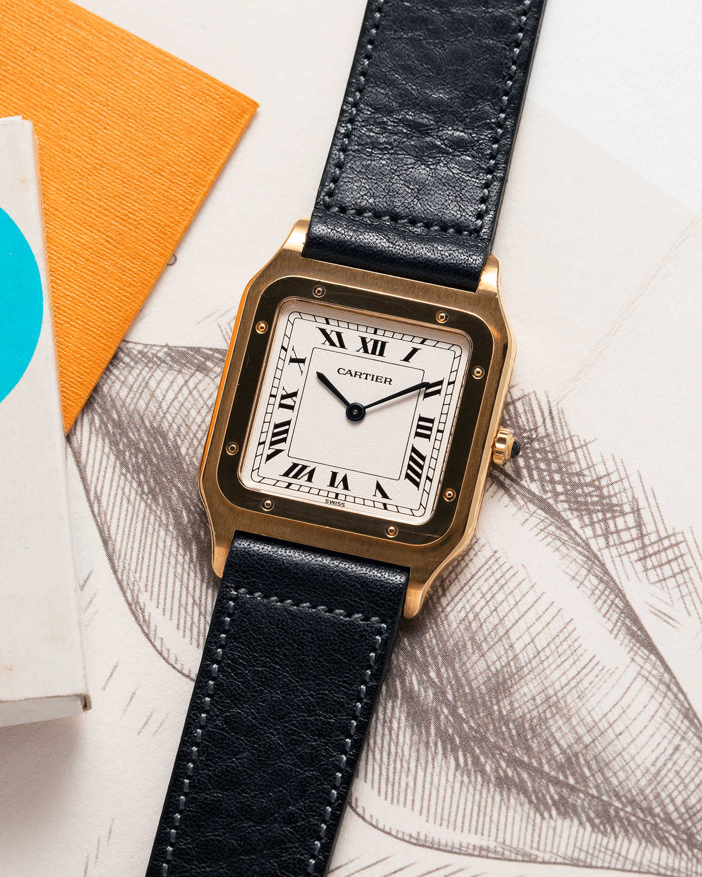 Brand: Cartier Year: 1990s Model: Santos Dumont Reference: 1576 Material: 18k Yellow Gold Movement: F.Piguet 21 Case Diameter: 27mm Strap: Accurate Form Navy Blue Japanese Calf and 18k Yellow Gold Cartier Deployant