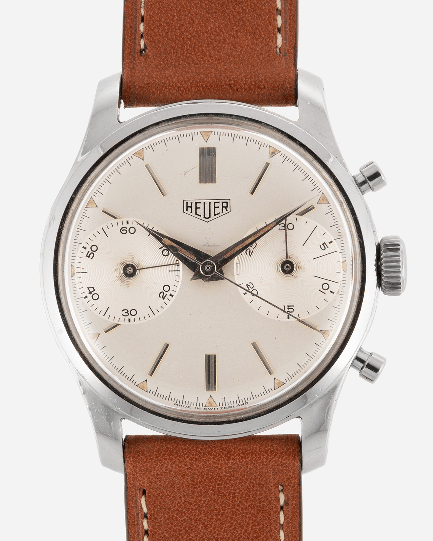 Brand: Heuer Year: 1950’s Reference Number: 404 Material: Stainless Steel Movement: Valjoux 23 Case Diameter: 34mm Lug Width: 18mm Bracelet/Strap: Nostime Gold Tan Barenia Smooth Calf