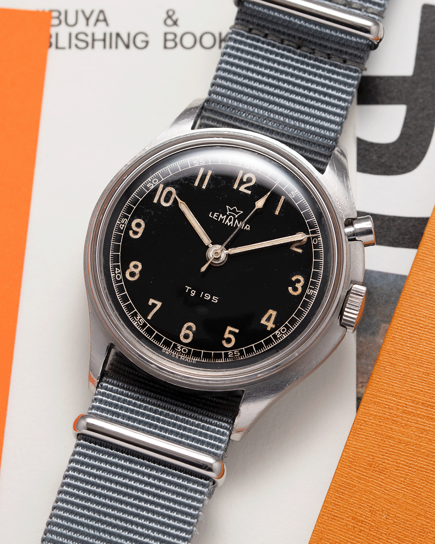 Brand: Lemania Year: 1957 Model: TG 195 Material: Stainless Steel Movement: Cal. 2225 Case Diameter: 40mm Lug Width: 20mm Bracelet/Strap: Grey NATO Strap